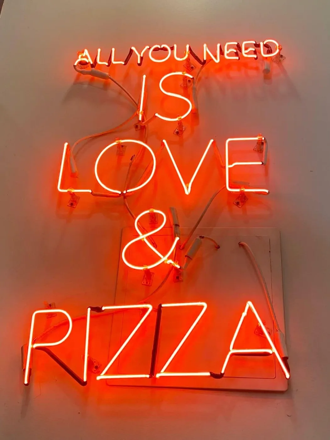 "All you need is love & pizza" neon sign inside Branch Pizza